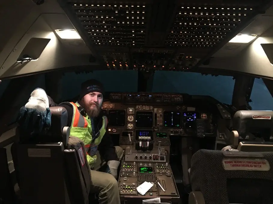 Portrait of Cody Quillia - CRAA employee sitting inside aircraft cockpit wearing a safety vest