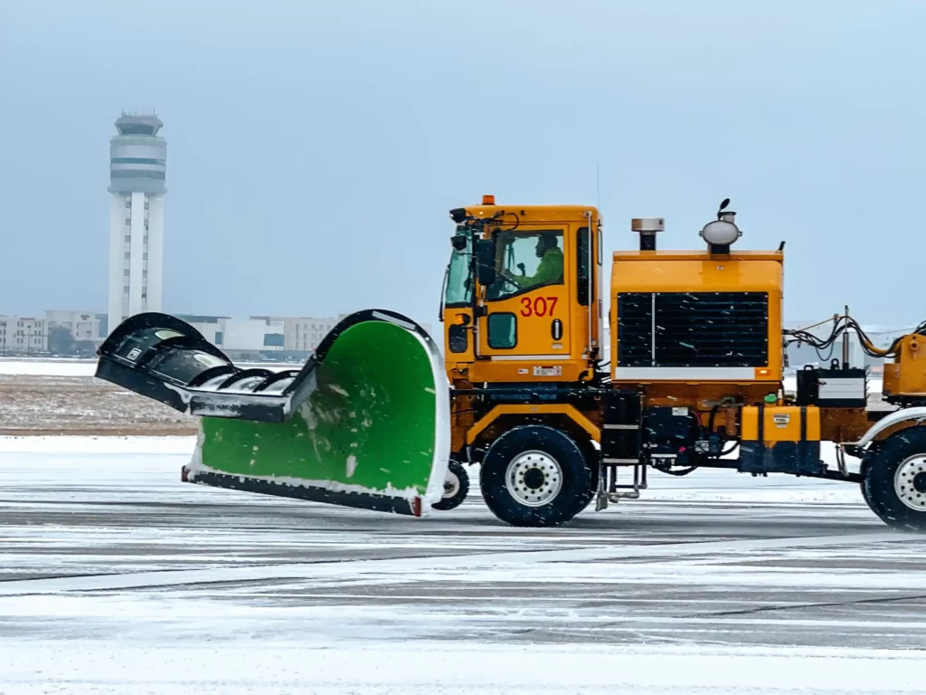 Yellow snow plow clearing the ramp during a snow storm at CMH airport