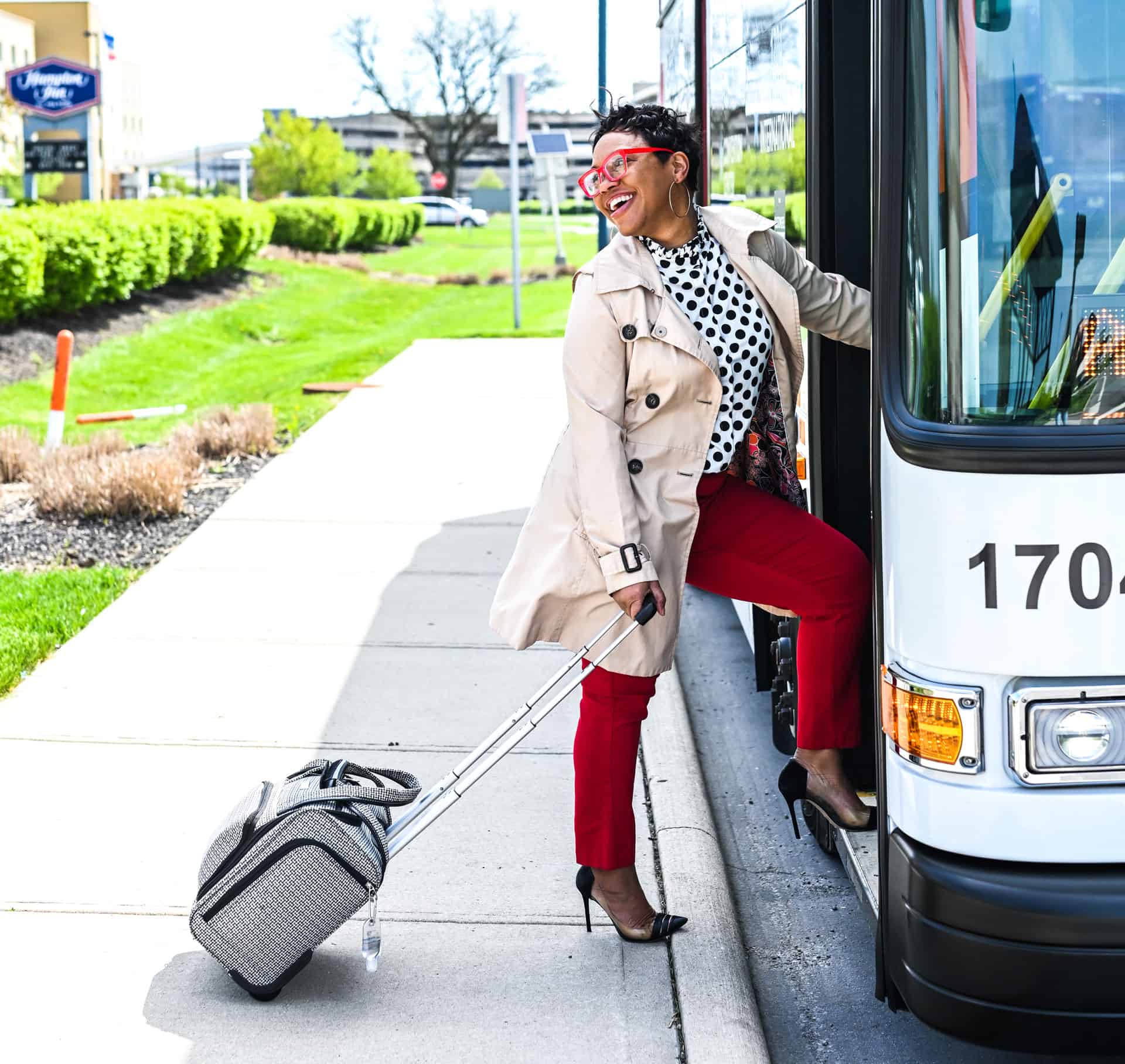 A woman boarding a bus with her luggage at CMH Airport.