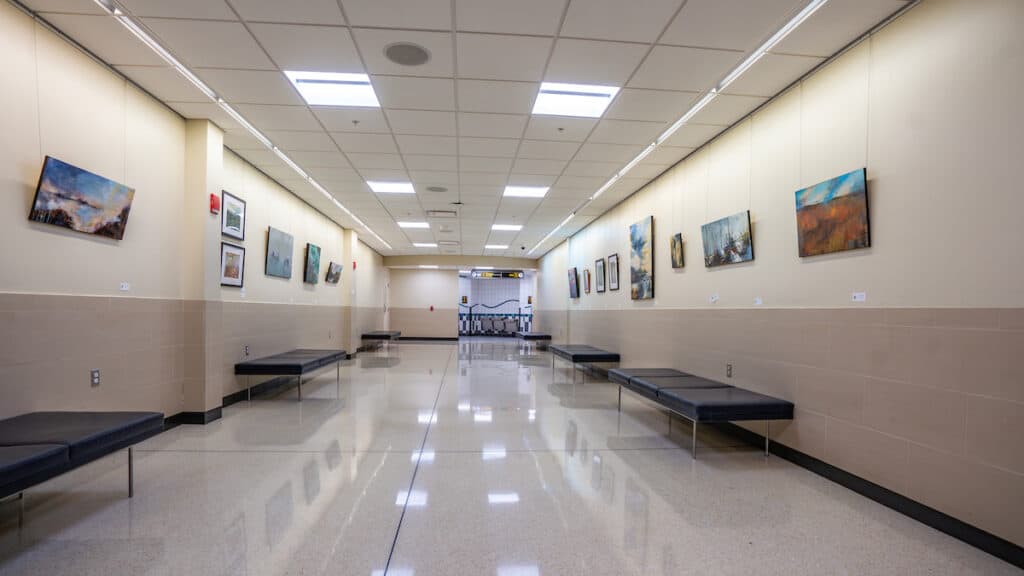 A hallway at John Glenn International (CMH) with benches and paintings on the wall.