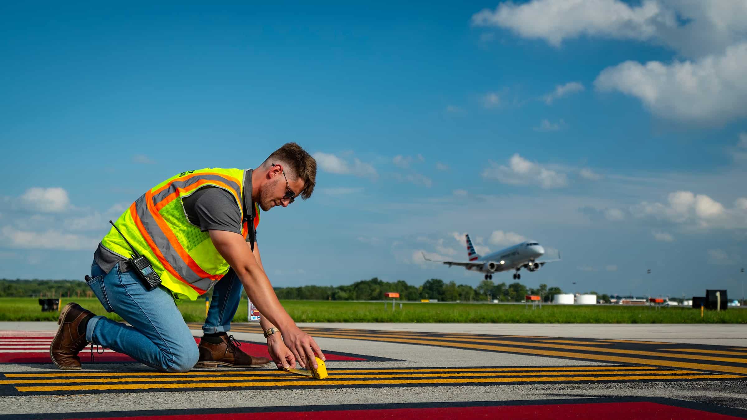 A man is laying down a runway at John Glenn International Airport.