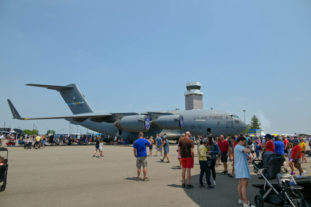A large group of people standing outside, around a large military airplane at the Columbus Air Show.