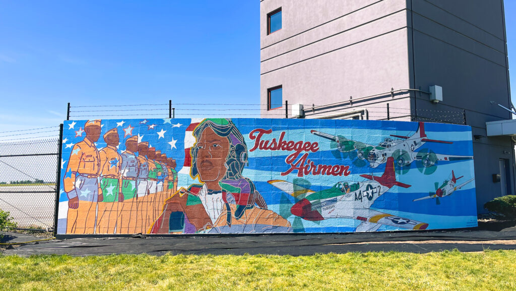 A vibrant mural depicting the Tuskegee Airmen with various military aircraft and personnel.