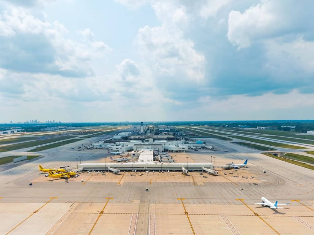 Aerial footage over the east ramp at John Glenn Columbus International Gateway. Below are several airplanes at gates. In the distance are darker clouds with downtown Columbus on the horizon.