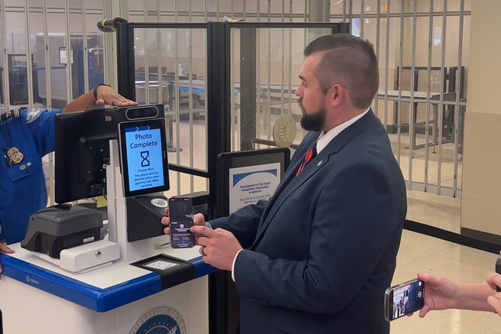 A government worker stands at a TSA kiosk and uses his mobile identification to pass through the security checkpoint.