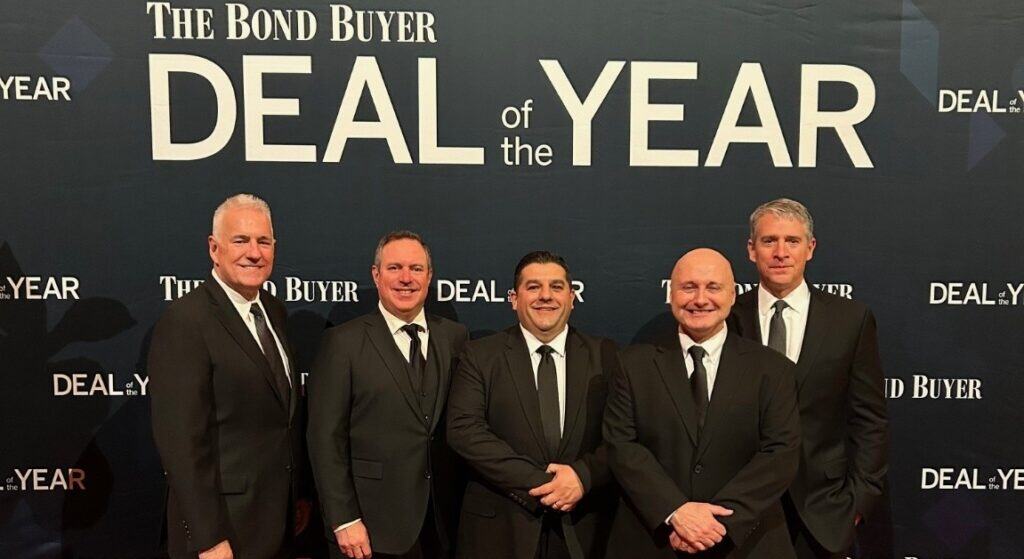 Joseph R. Nardone, President & CEO; William Case, Managing Director, Business Development, PFM; Fabio Spino, Chief Financial Officer; Tom McCarthy, Chief Planning & Engineering Officer; and Kevin McPeek, Director, PFM pose together on a red carpet in front of a Bond Buyer Deal of the Year wall.