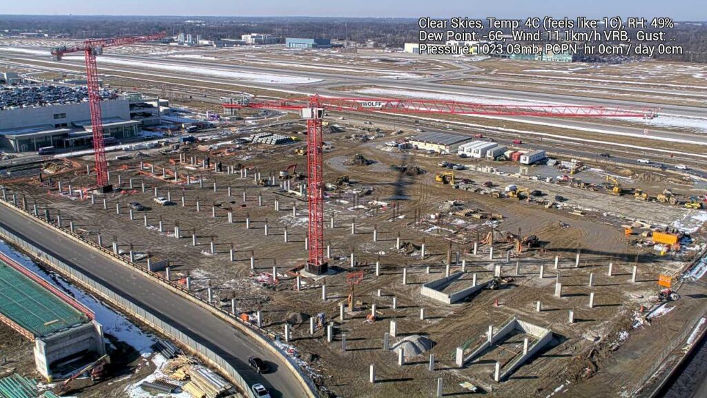 An aerial view of a construction site with several columns placed in dirt.