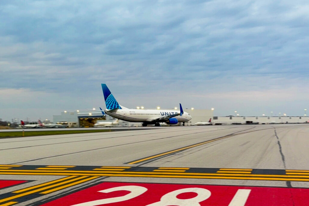 A United Airlines Boeing 737-900 blasts down the runway on a cloudy morning.
