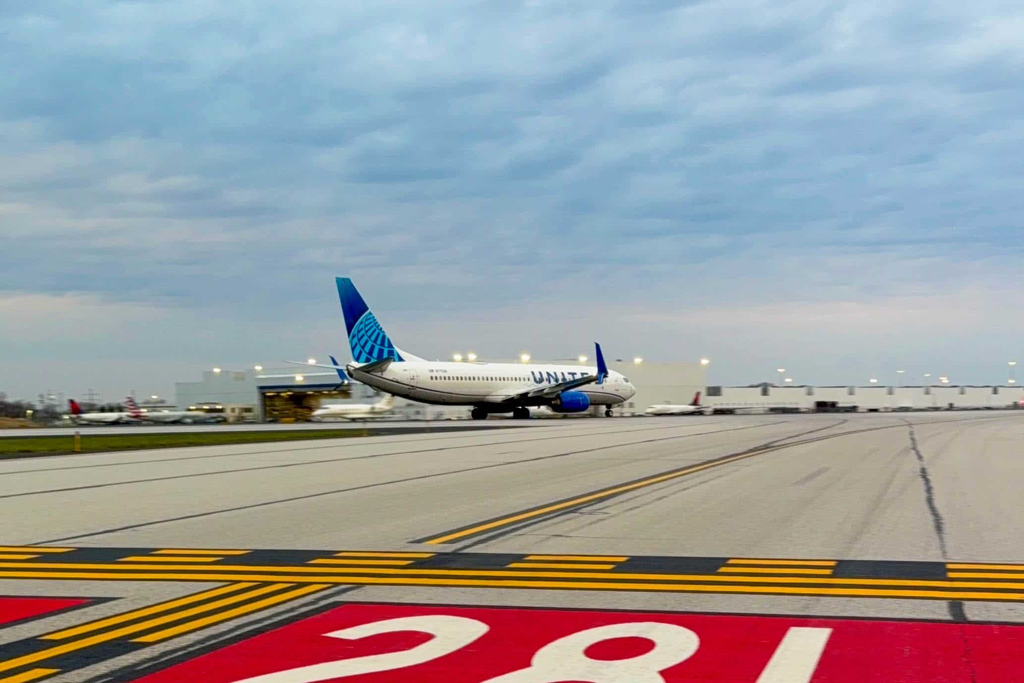 A United Airlines Boeing 737-900 blasts down the runway on a cloudy morning.