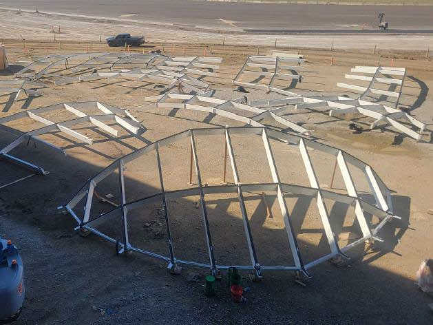 Aerial view of curved steel framing pieces laid out across the CMH Next construction site, ready for installation as part of the new terminal.