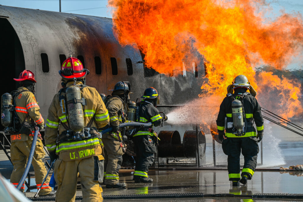 Rickenbacker airport emergency exercise; a team of firefighters moving toward an airplane on fire and extinguishing the flames.
