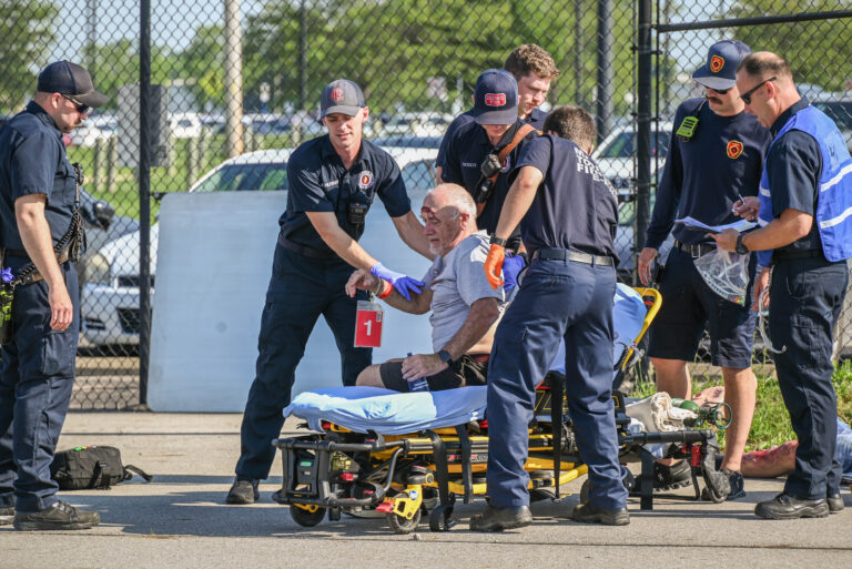 EMTs and emergency workers help a man onto a stretcher.