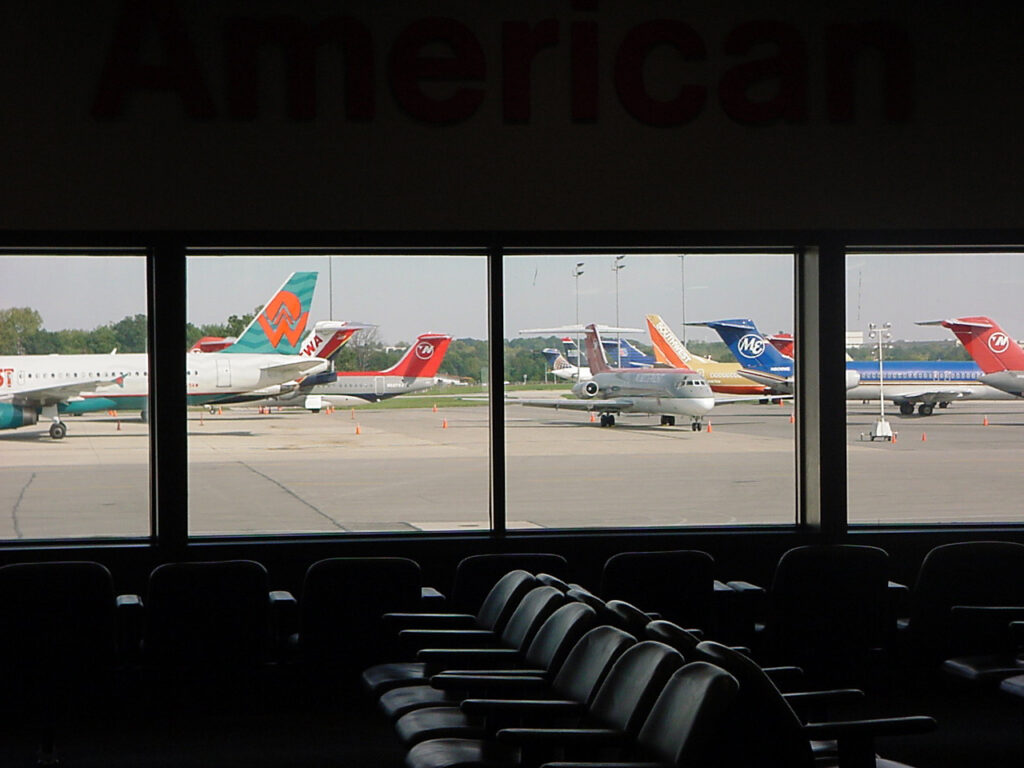 View from inside the airport terminal looking through large windows at several commercial airplanes parked on the airfield, representing air travel the day of the September 11, 2001 attacks.