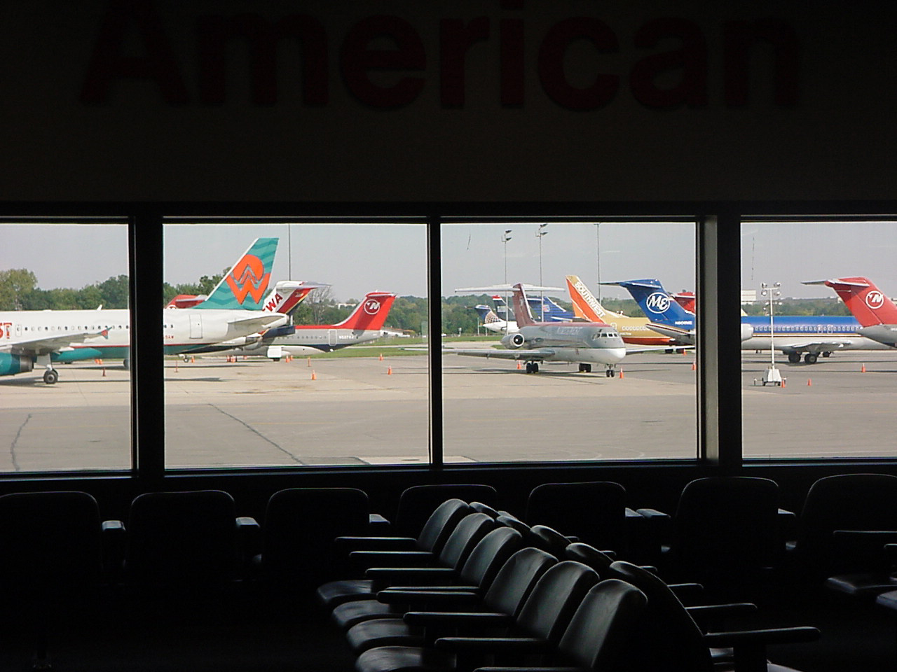 View from inside the airport terminal looking through large windows at several commercial airplanes parked on the airfield, representing air travel the day of the September 11, 2001 attacks.