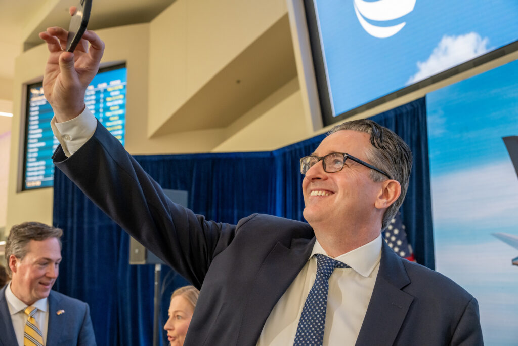 Lufthansa’s Derk Janzen takes a selfie onstage with Lufthansa signs in the background.